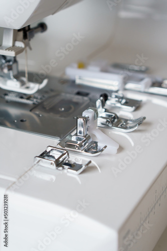 White modern ewing machine and its components close up. Sewing needle plate and replacement parts