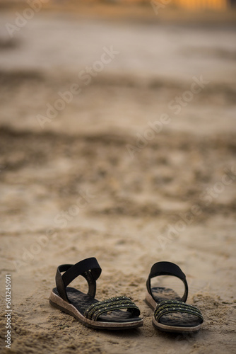 Summer concept with sandy beach and black sandals