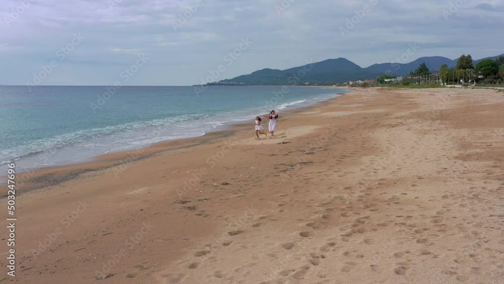Happy mom with her beloved children run along the beach on summer vacation. Family, vacation and travel concept. Happy mom with her beloved children run along the beach on summer vacation. Family, vacation and travel concept.