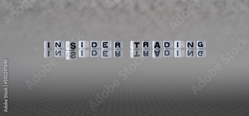 insider trading word or concept represented by black and white letter cubes on a grey horizon background stretching to infinity