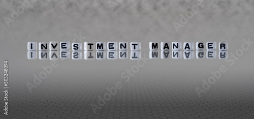 investment manager word or concept represented by black and white letter cubes on a grey horizon background stretching to infinity
