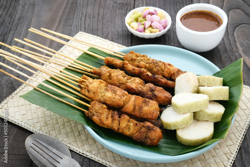 Chicken satay (sate ayam) with Lontong and peanut sauce. One of the popular street food in Indonesia. Selective focus.
