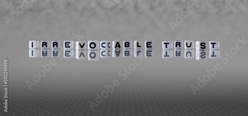 irrevocable trust word or concept represented by black and white letter cubes on a grey horizon background stretching to infinity photo