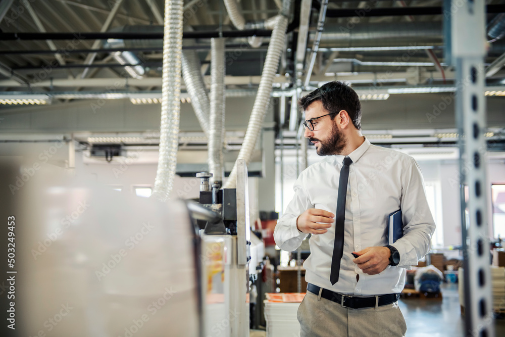 A supervisor walking around printing shop and checking on machines. A supervisor walking around printing shop and checking on machines.