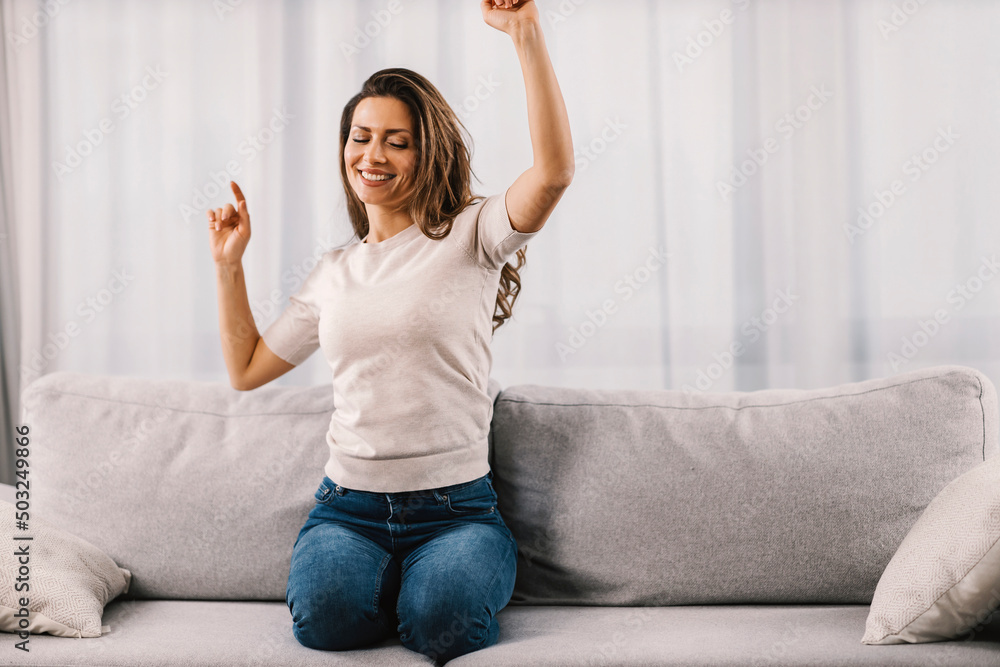 A woman dances on the sofa at home. A woman dances on the sofa at home.