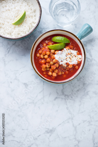 Indian chana masala or chole masala with basmati rice, flat lay on a light-grey marble background, vertical shot, copy space