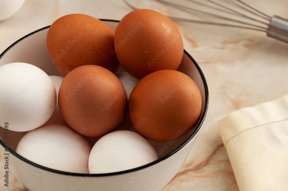 Eggs in a ceramic cup close-up. Cooking in the kitchen. White and brown eggs. selective focus Eggs in a ceramic cup close-up. Cooking in the kitchen. White and brown eggs. selective focus