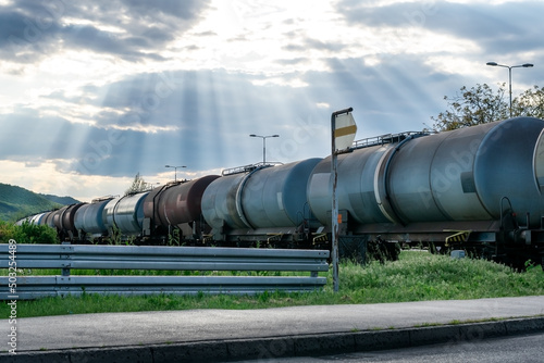 Railroad train of tanker cars transporting crude oil on the tracks under a beautiful dramatic sky.