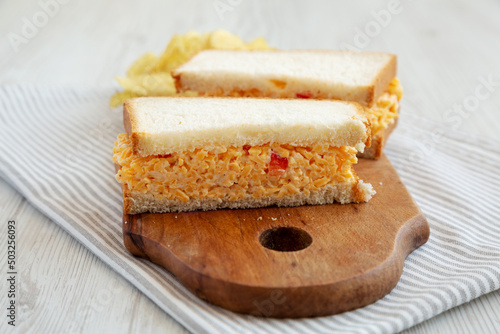 Homemade Pimento Cheese Sandwich with Chips on a rustic wooden board, side view. Close-up. photo