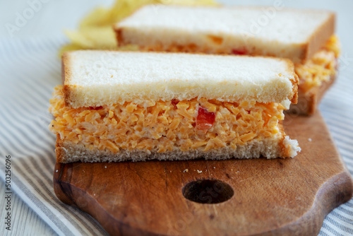 Homemade Pimento Cheese Sandwich with Chips on a rustic wooden board, low angle view. Close-up.