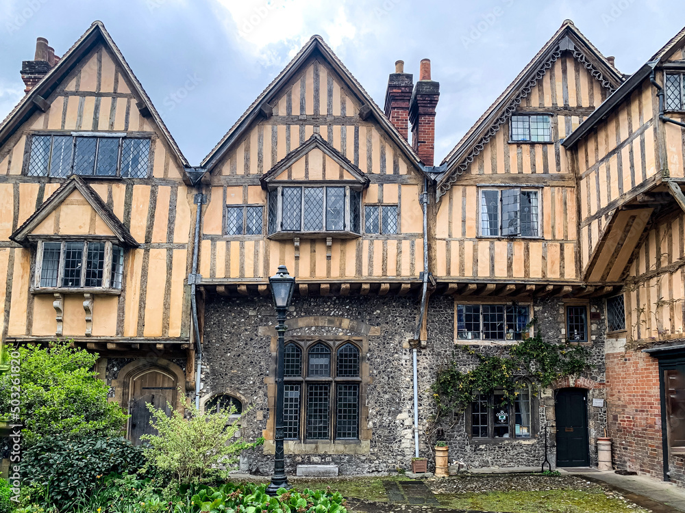 Cheney Court and old medieval stables view in Winchester. Half timbered tudor architecture. Yellow half timbered tudor house near Cathedral in Winchester. Stables. Through the gate.