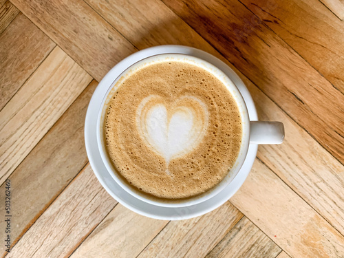 A cup of coffee latte On a wooden table. A mug of flat white coffee on a wooden background. Coffee art. Heart flower shape latte art. Copy space