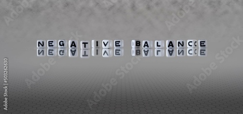negative balance word or concept represented by black and white letter cubes on a grey horizon background stretching to infinity