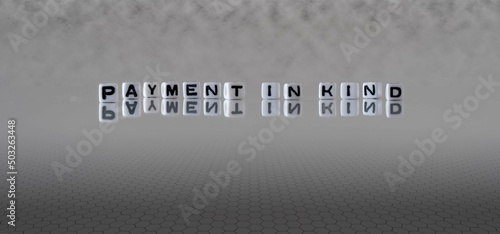 payment in kind word or concept represented by black and white letter cubes on a grey horizon background stretching to infinity