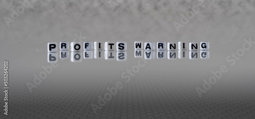 profits warning word or concept represented by black and white letter cubes on a grey horizon background stretching to infinity