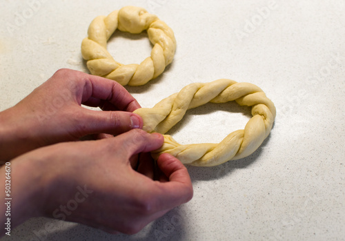 Female hands braiding dough on white table