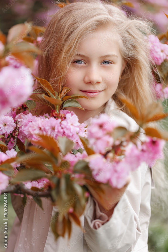 Very tender portrait of a beautiful girl in the flowering branches of Japanese sakura. Women's holiday with a girl in sakura