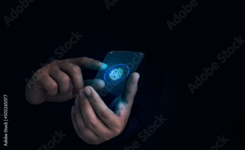 Fotografija Finger scan icon appeared while man's finger touched on futuristic transparent glass smart mobile phone on dark background