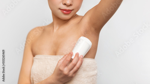 Young Asian woman using applying deodorant in bathroom