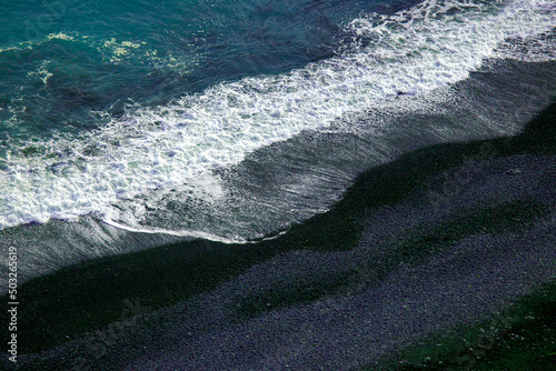 Waves of the Atlantic ocean fall on the black sand of the beach of Iceland from a height