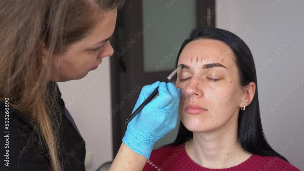 a young woman gets eyebrow dye applied to her hair. eyebrow tinting with henna close-up a young woman gets eyebrow dye applied to her hair. eyebrow tinting with henna close-up