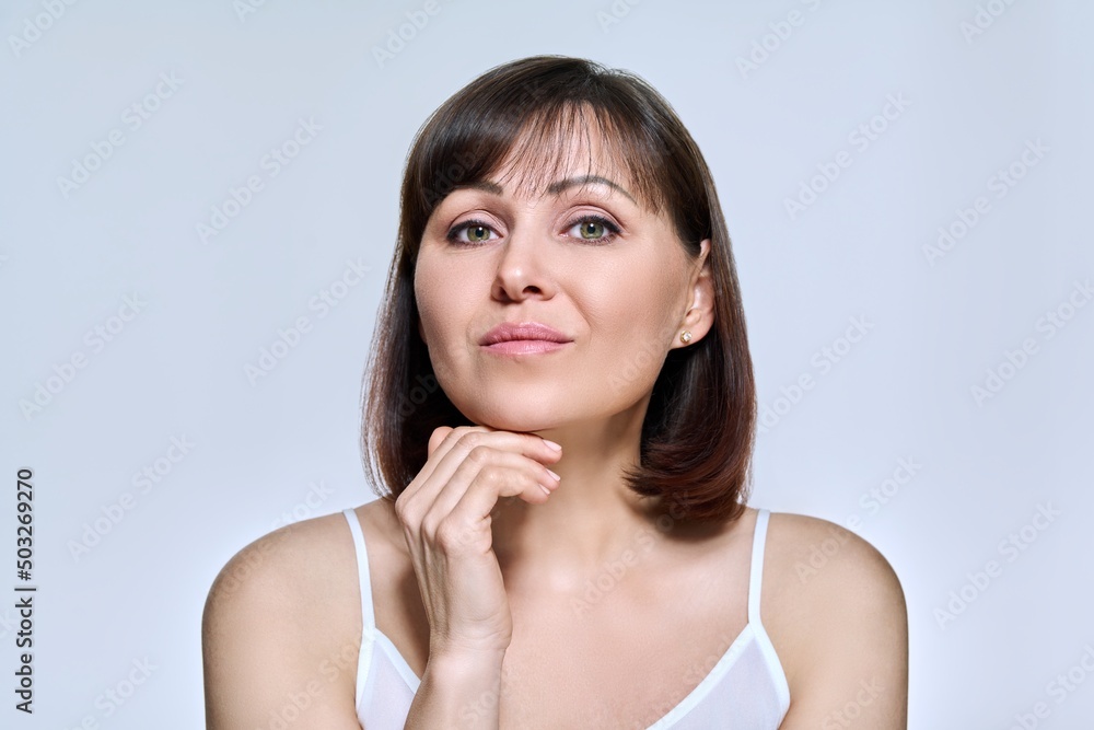 Portrait of middle aged woman looking at camera on light studio background Portrait of middle aged woman looking at camera on light studio background