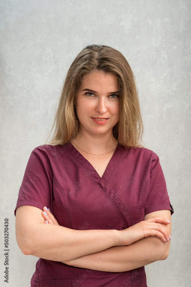 Portrait of young female masseur in uniform. Attractive girl with natural appearance and long hair. Vertical frame. Portrait of young female masseur in uniform. Attractive girl with natural appearance and long hair. Vertical frame.