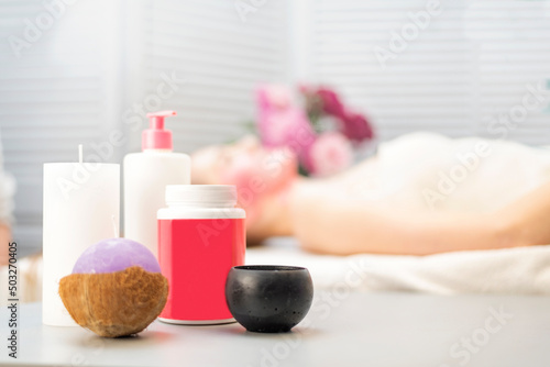 Scented candles and cosmetics in Spa salon. Girl during the performance of cosmetic procedures on the background.