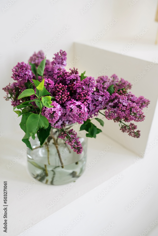 Fototapeta premium Fresh lilac branches in a vase in a bright interior