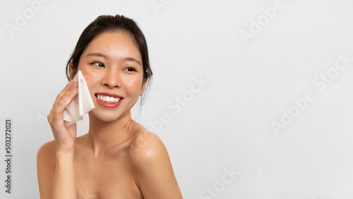 Young Asian lady rubbing her face with napkin
