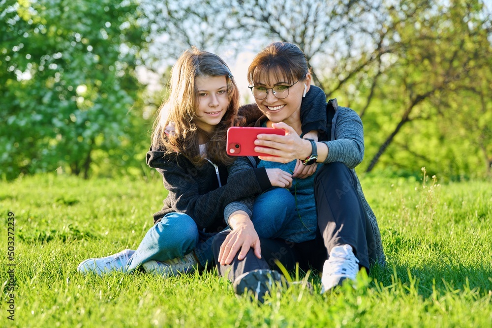 Mom and daughter looking together at smartphone screen, outdoor Mom and daughter looking together at smartphone screen, outdoor