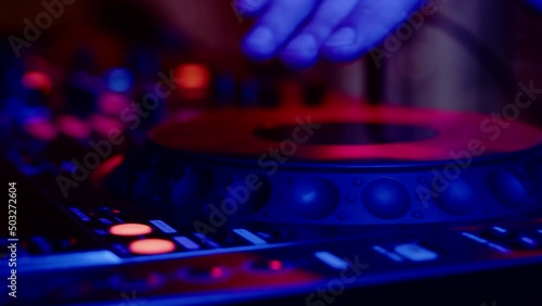 Closeup of Dj mixer control panel at disco in nightclub. DJ spins vinyl record on his remote control in nightclub at party photo