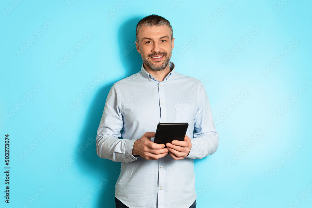 Middle Aged Businessman Holding Digital Tablet Standing Over Blue Background Middle Aged Businessman Holding Digital Tablet Standing Over Blue Background