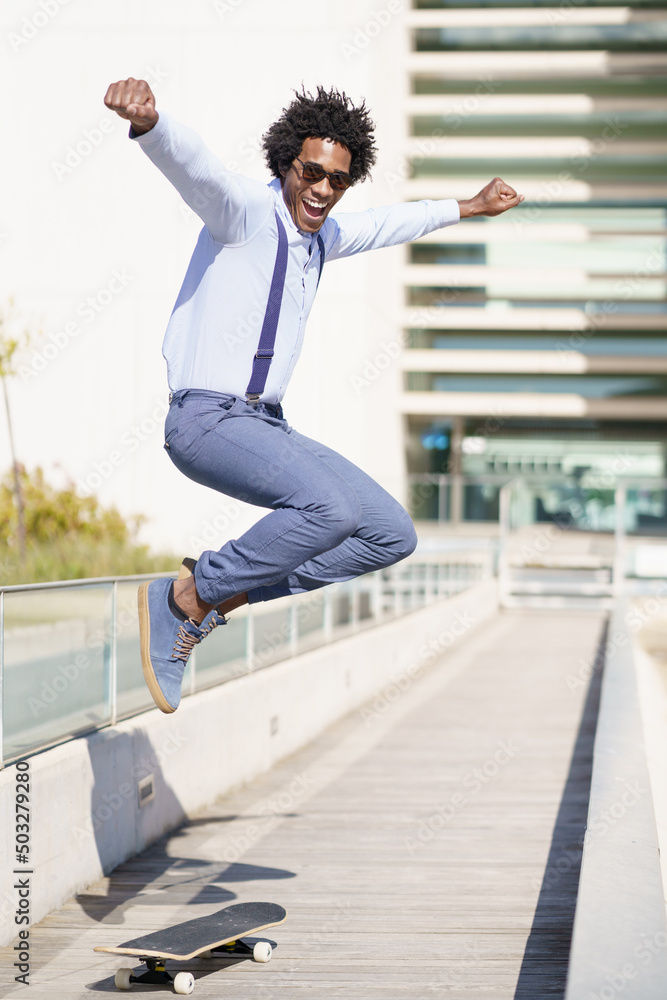 Cheerful black man riding skateboard and jumping