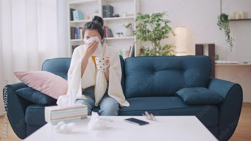 Asian woman suffering flu and runny nose, sneezing and running a fever at home Asian woman suffering flu and runny nose, sneezing and running a fever at home