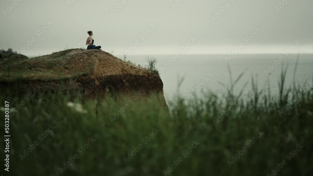 Far view yoga woman exercising on hill top. Girl meditating sitting lotus pose. Far view yoga woman exercising on hill top. Girl meditating sitting lotus pose.