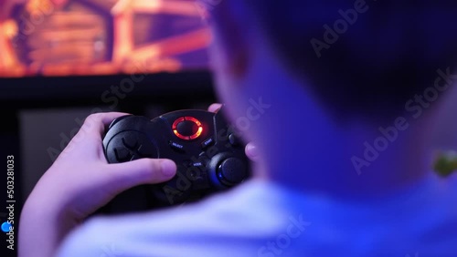 Gamer boy playing video games online on a computer in a dark room