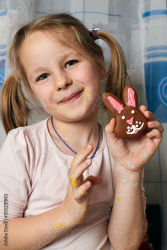 Little beautiful girl shows gingerbread, which she made herself.