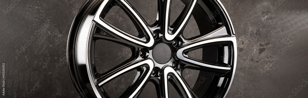 glossy black alloy wheels fragment on a textured black background