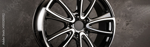 glossy black alloy wheels fragment on a textured black background