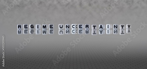regime uncertainty word or concept represented by black and white letter cubes on a grey horizon background stretching to infinity