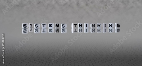 systems thinking word or concept represented by black and white letter cubes on a grey horizon background stretching to infinity