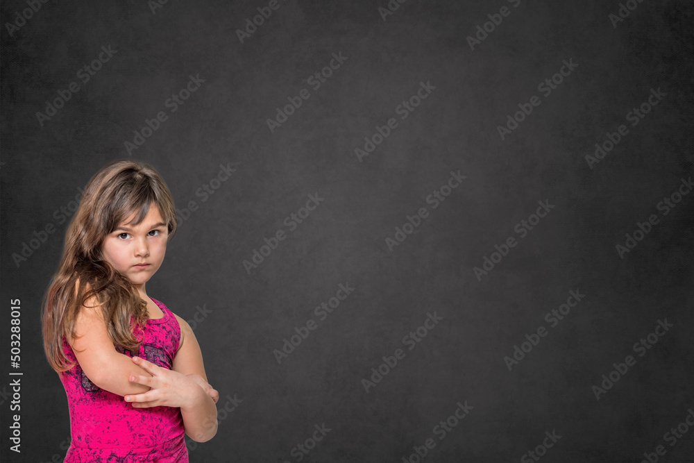 Serious long haired little girl is posing on the dark background. Horizontally. Serious long haired little girl is posing on the dark background. Horizontally.