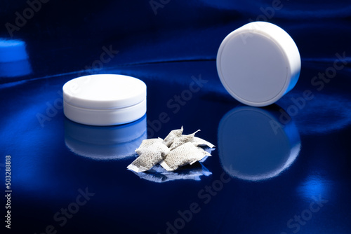 Closeup of white Swedish snus pouches against a blue background. Smokeless tobacco.