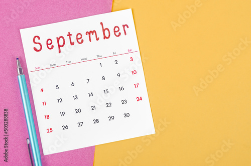 September 2022 calendar  with pen on multicolored background.