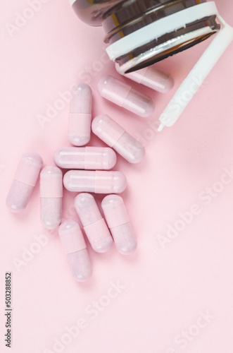 Pink capsule pills with bottle on pink background