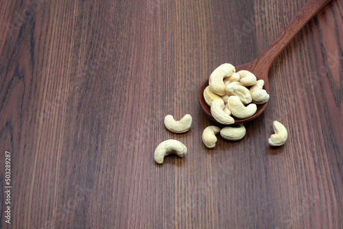 Roasted cashew nut in spoon on wooden texture background