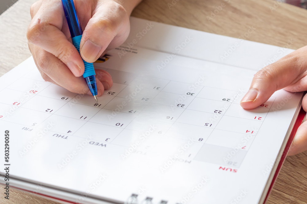 Woman hand with pen writing on calendar date business planning appointment meeting concept Woman hand with pen writing on calendar date business planning appointment meeting concept