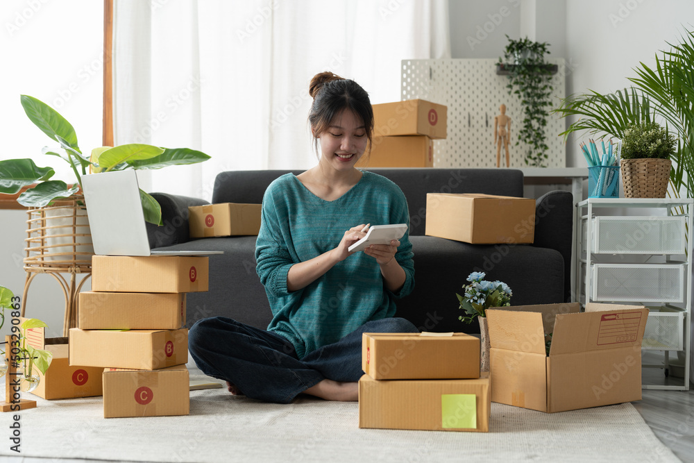 Entrepreneur using calculator with pencil in her hand, calculating financial expense at home office,online market packing box delivery,Startup successful small business owner, SME, concept Entrepreneur using calculator with pencil in her hand, calculating financial expense at home office,online market packing box delivery,Startup successful small business owner, SME, concept