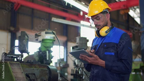Professional maintenance engineer, technician worker, repairman wear uniform, safety hard hat using tablet computer checking control machine in factory. Manufacturing heavy machine Industry concept.